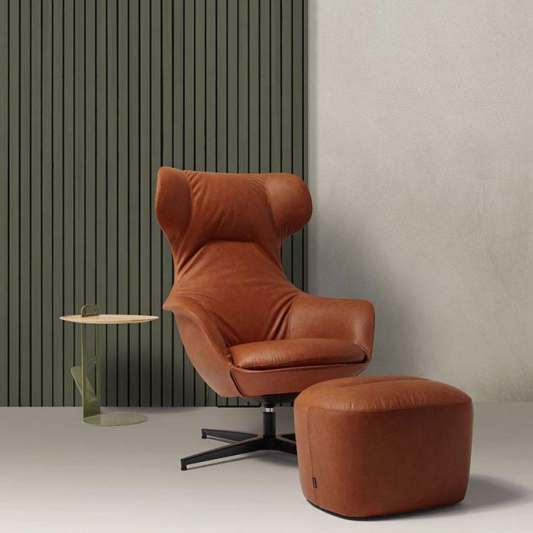 Cognac leather Italian office chair with matching ottoman and side table in a modern executive workspace