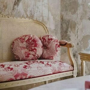 Elegant traditional settee with cane back and red toile upholstery in distressed interior.