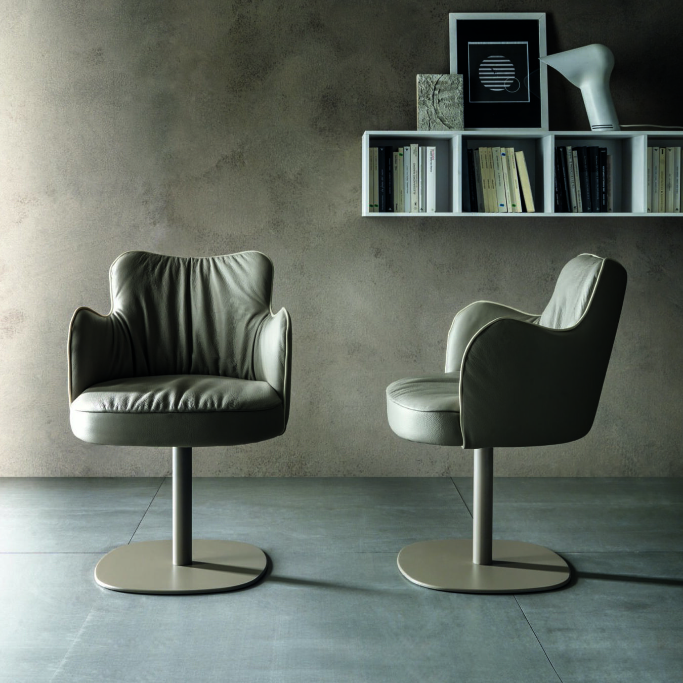 Two leather Italian hotel furniture armchairs with pedestal bases styled in a sophisticated hospitality interior setting.